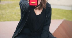 woman in black long sleeve shirt and black pants holding iphone